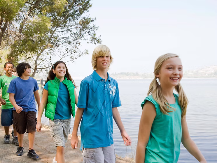 Young people walking together outdoors by a lake on a sunny day